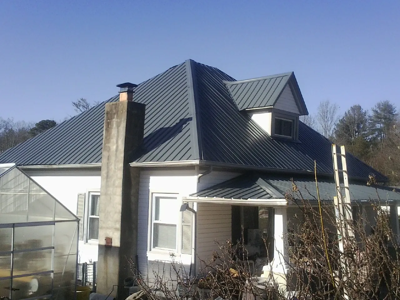 Dark blue standing seam metal roof on a white farmhouse with dormer — Slate & Tile Roof Repair by Roofing Brothers in Stone Ridge