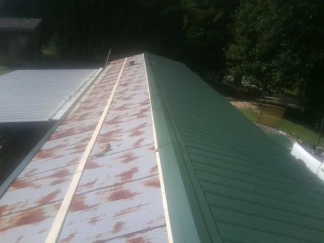 Old rusted panels beside newly installed green metal roofing — Wind Damage Roof Repair by Roofing Brothers in Stone Ridge