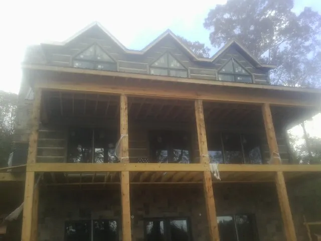 Dormers and porch framing on a large log home under construction — Roof Coating work by our crew in Stone Ridge