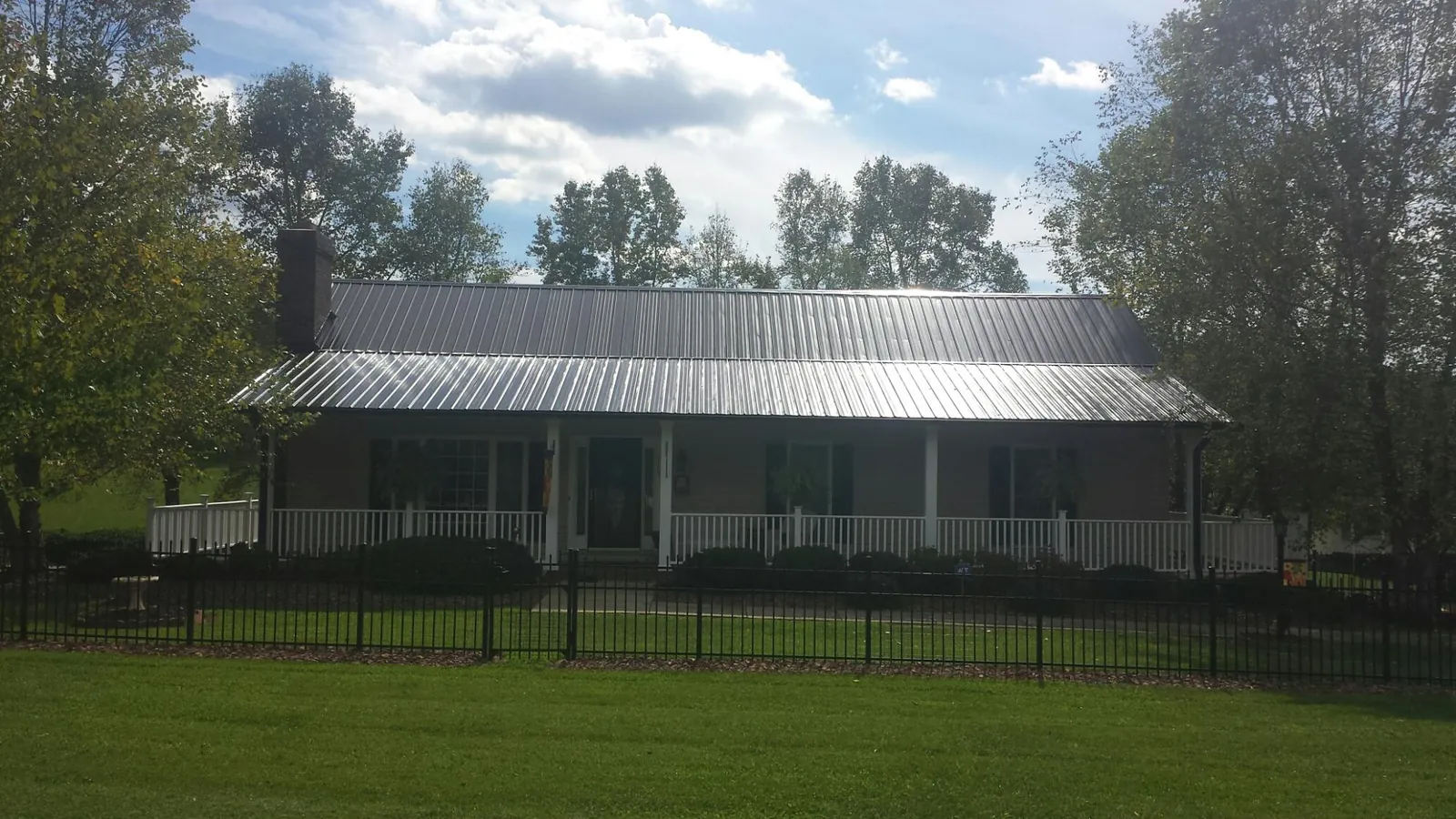 Gray metal roof on a brick ranch with a full width front porch — Gutter Guard Installation work by our crew in Stone Ridge