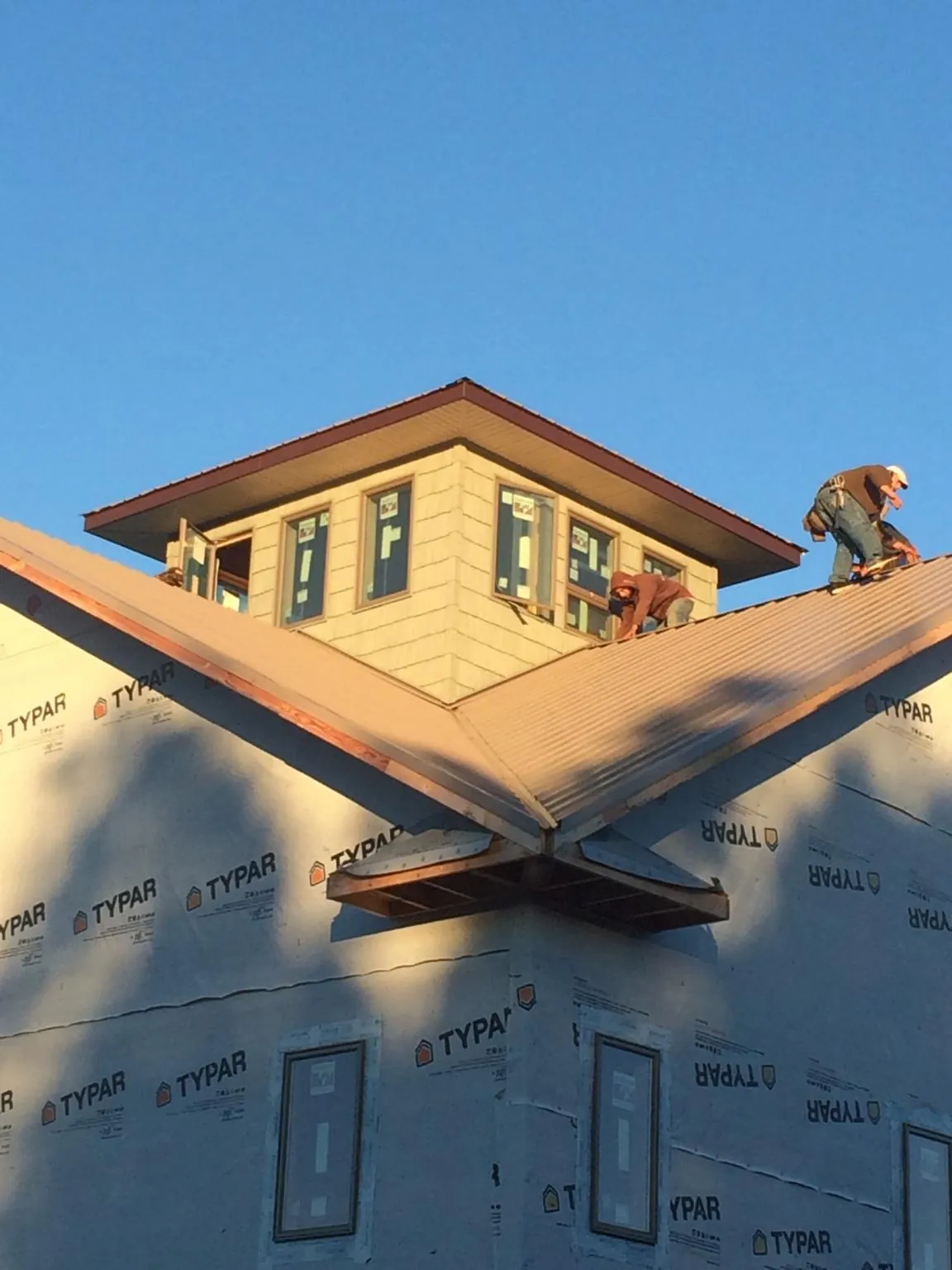 Roofers working around a rooftop cupola on a new metal roof at sunset — Roof Waterproofing in Stone Ridge by Roofing Brothers